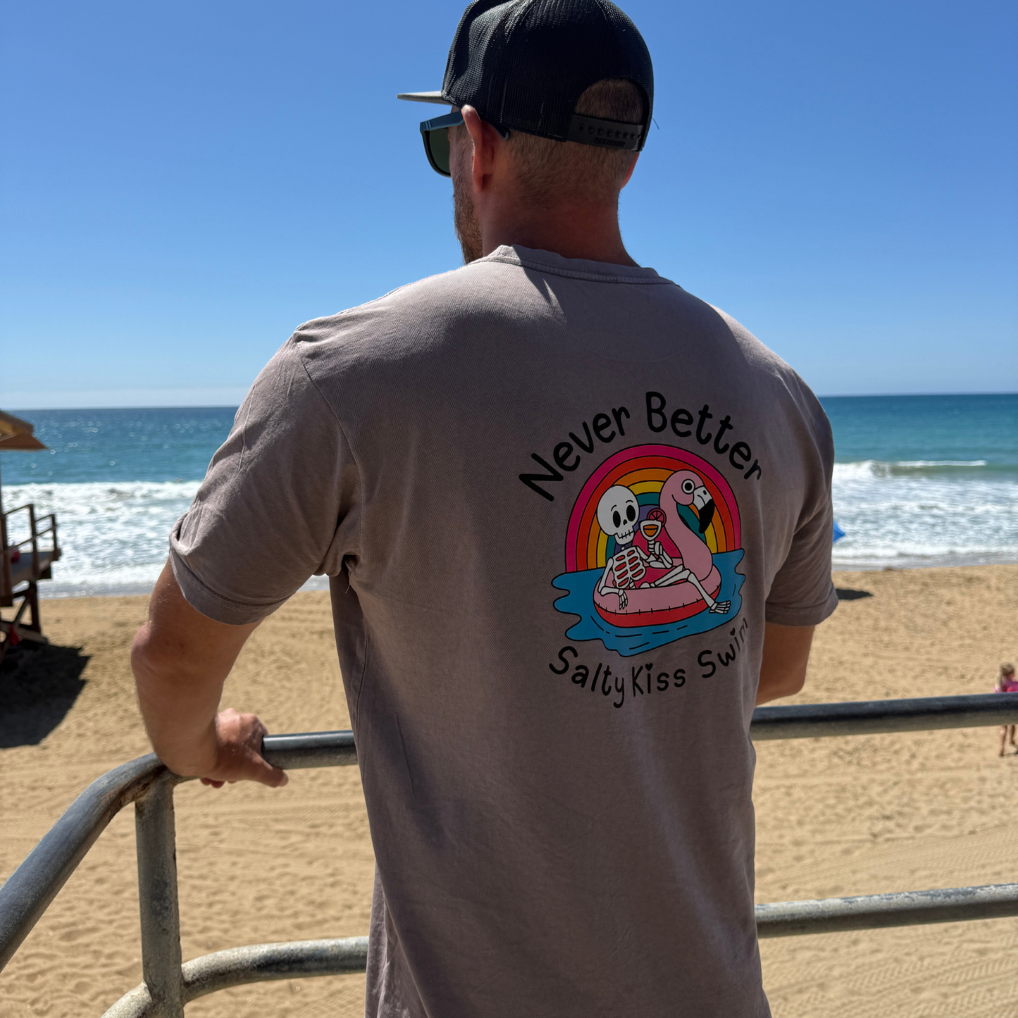Man wearing a t-shirt with a graphic design of two cartoon characters on a beach.