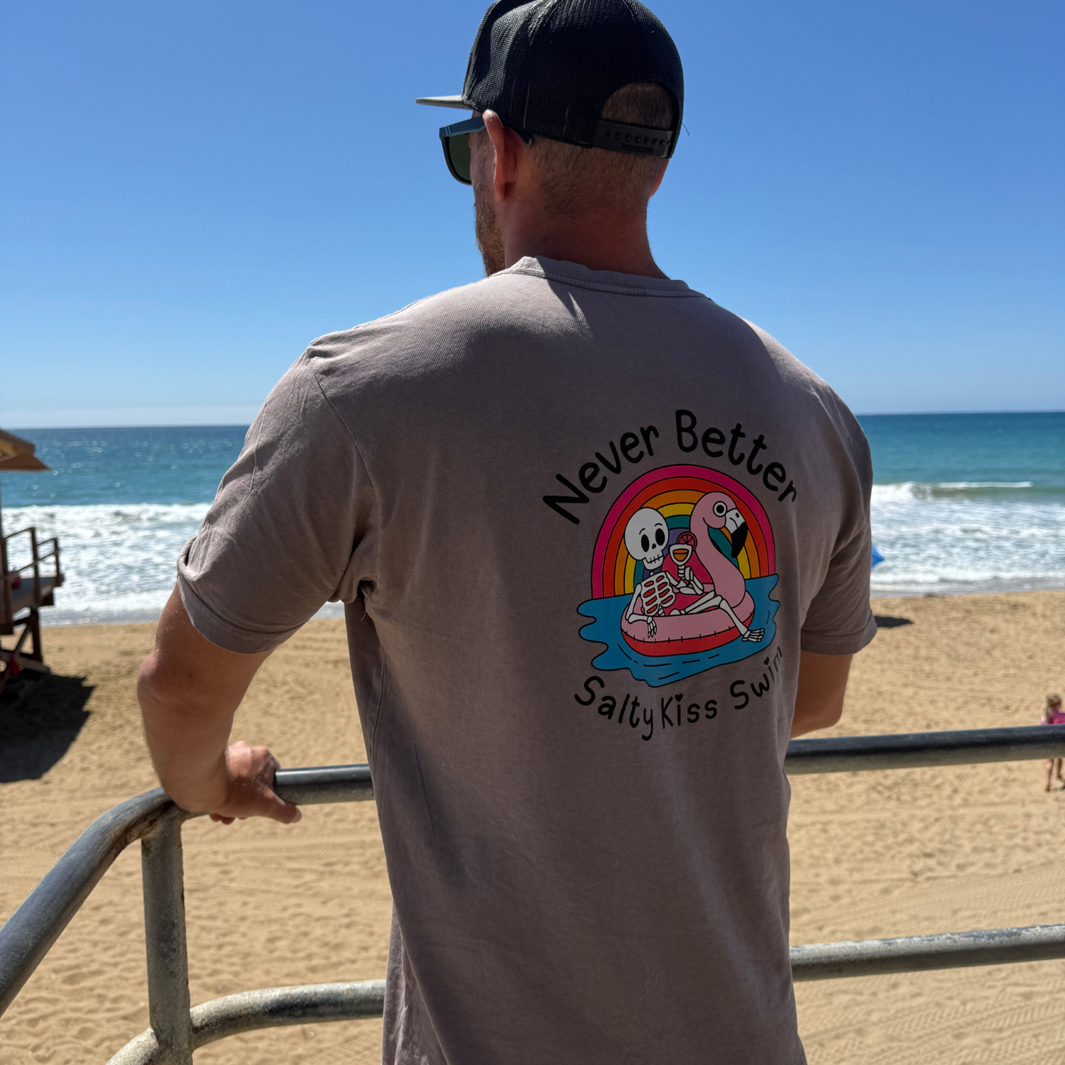 Man wearing a t-shirt with a graphic design of two cartoon characters on a beach.